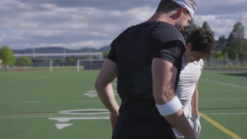 A group of men talk and move around the field