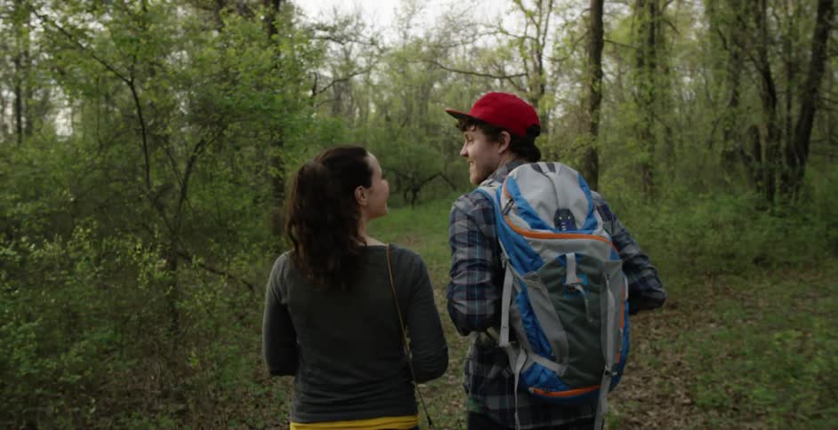 A man and a woman hiking along a path in the woods