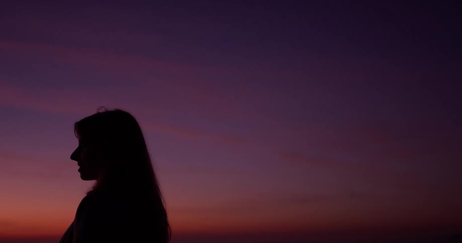 Woman stands outside at sunset