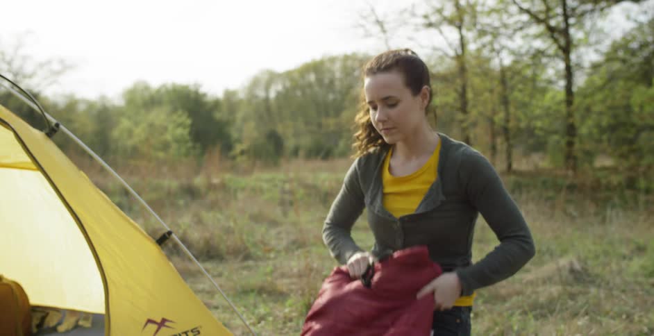 A man and woman pack up items from their camp site
