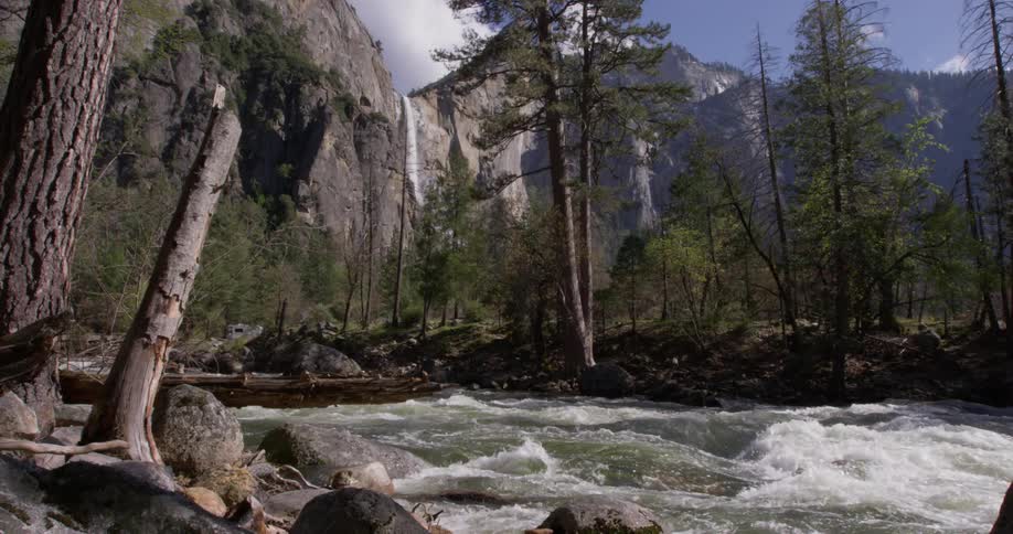 Water splashes through trees near mountains
