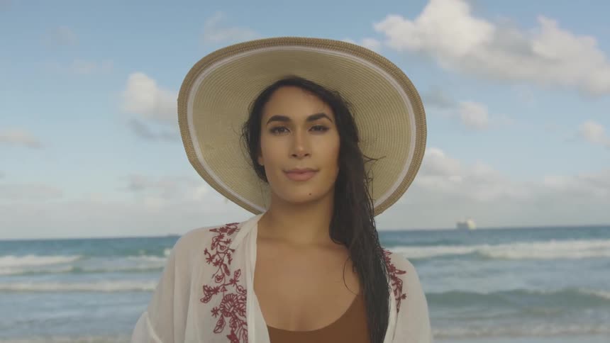 The woman smiles by the rough waters