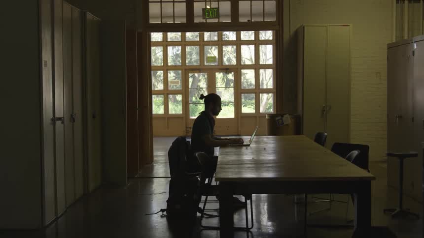 A man works on a laptop on a dining room table