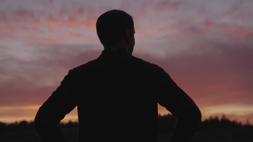 Man stands and looks out at the darkening sky