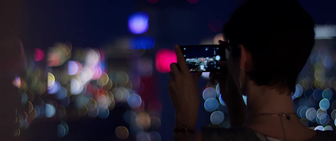A woman takes a picture of city lights at night