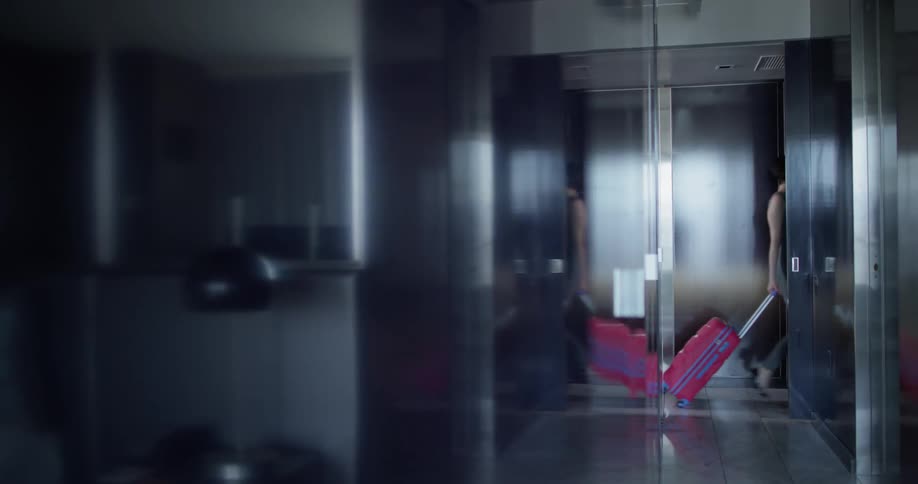 A woman walks down the hall with luggage
