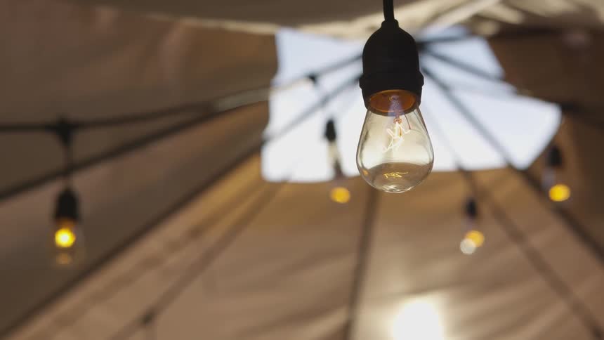 A string of lights hang in a tent with an opening at the top