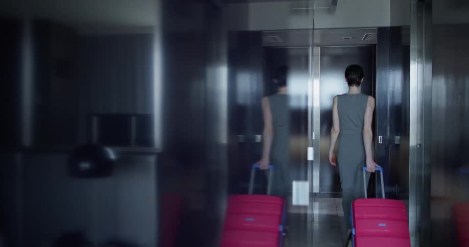 A woman goes down the hallway with her luggage