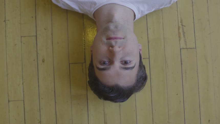 A man blinks his eyes while laying on the floor