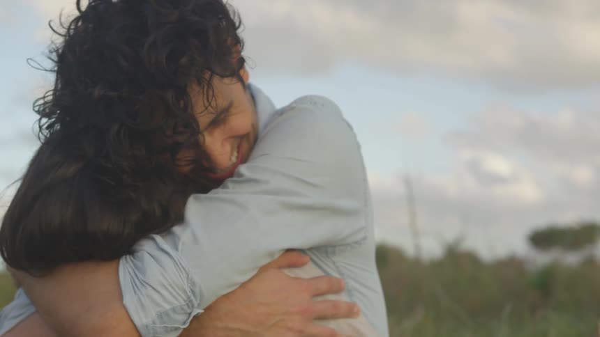 A man is hugging a woman outside on a cloudy day