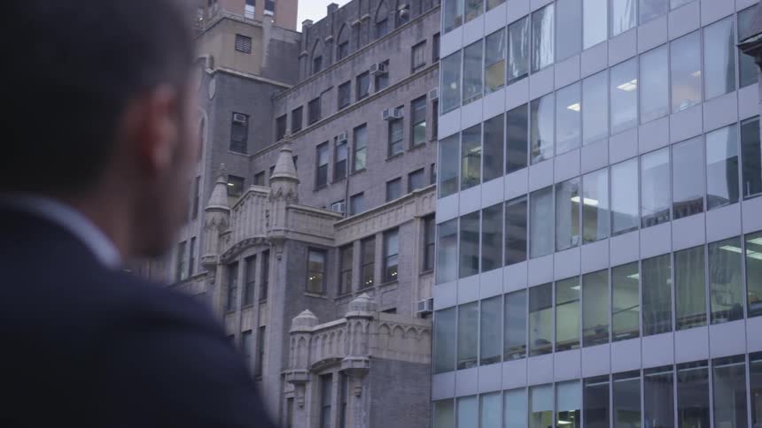 The man looks across the way at the buildings