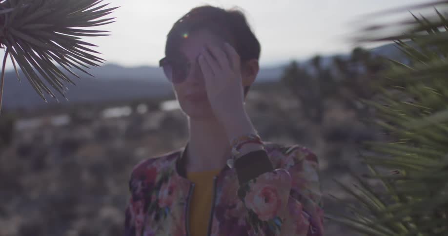 A woman smiles wearing sunglasses in the desert