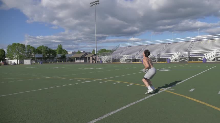 A football player catches a football and runs on an outdoor field