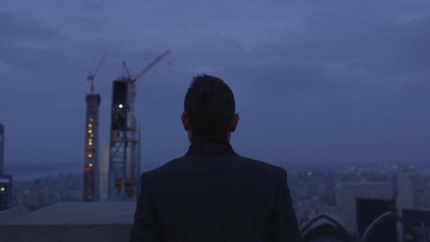 A man stands outside in a city at night