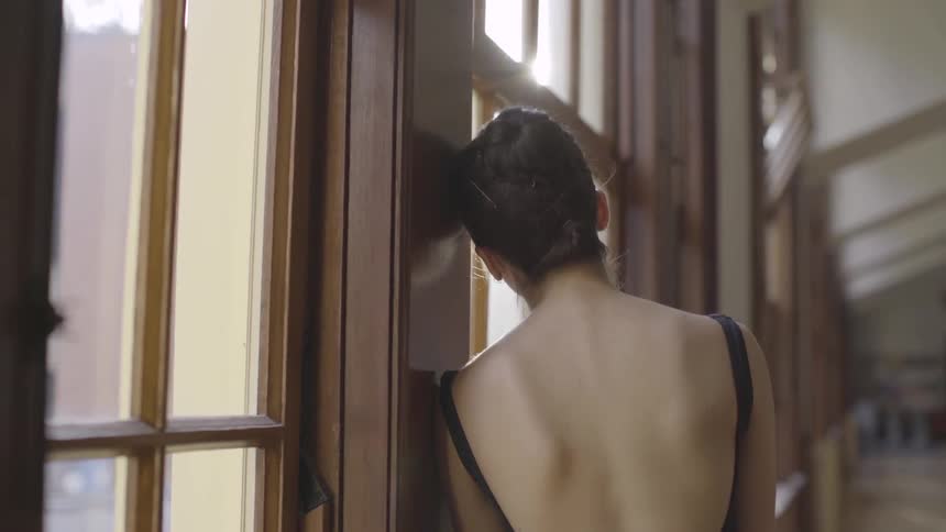 A woman leans against the window in the hall