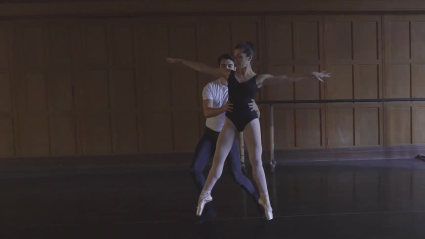 Man and woman practice ballet dancing in an empty room