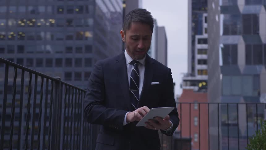 A man uses his tablet on the balcony