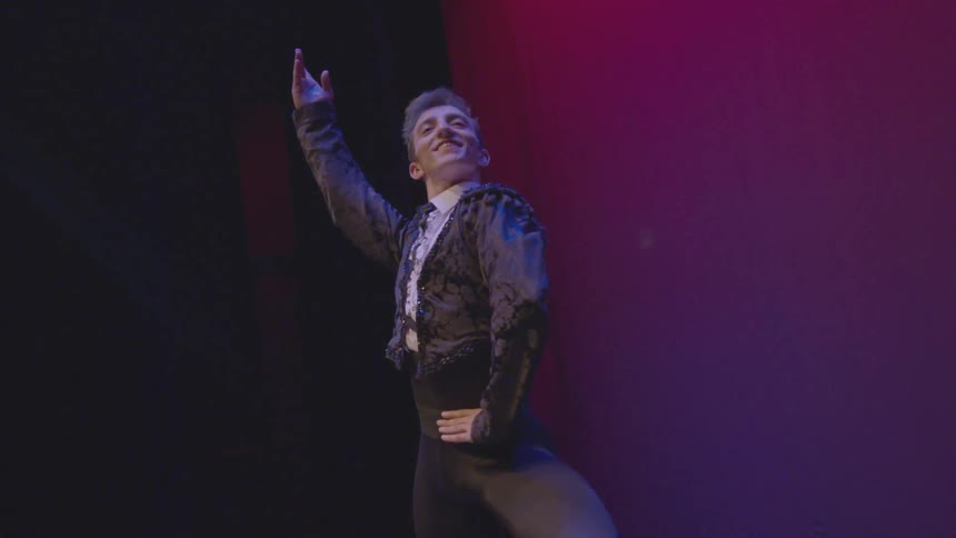 A man leans forward raising his arm on stage