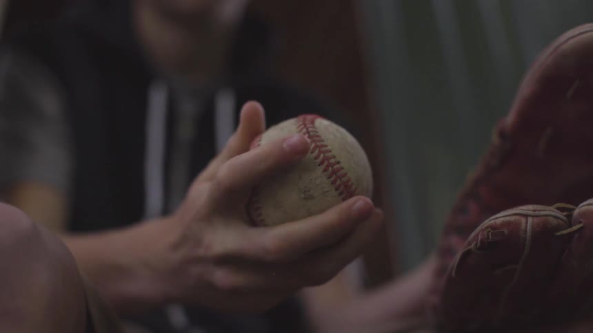 A teenager holds a baseball and mitt