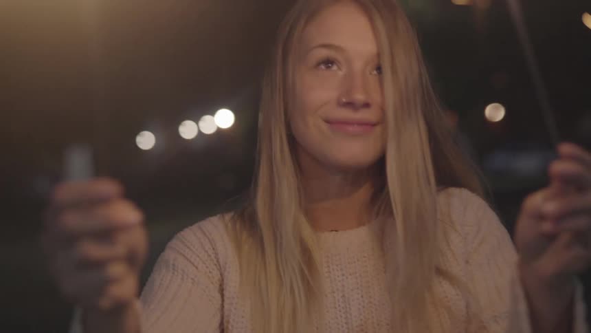 A girl laughs as she plays with sparklers outside