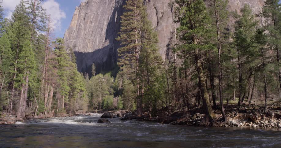 Water splashes over rocks through the trees near the mountains