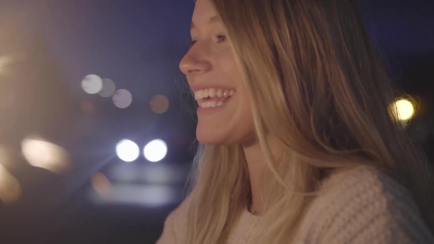 A woman smiles while holding a burning sparkler at night