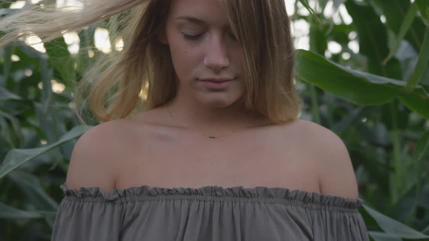 Woman with long hair stands near the corn stalks