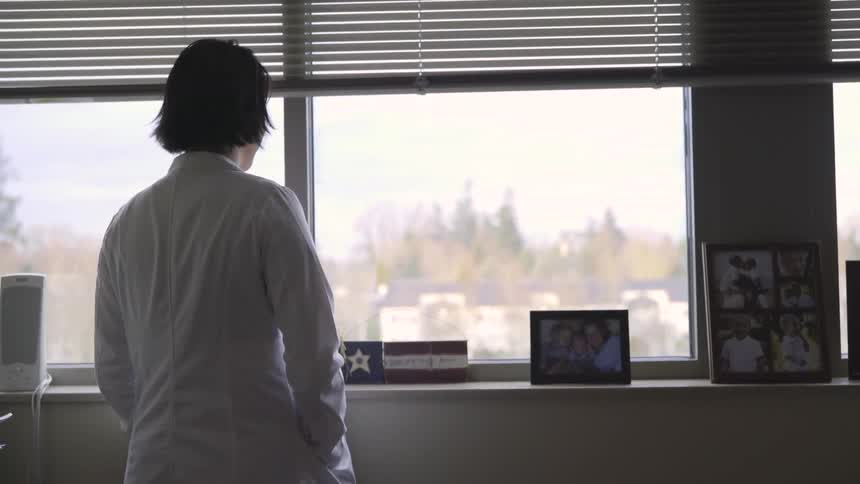 Woman looks out an office window at a city