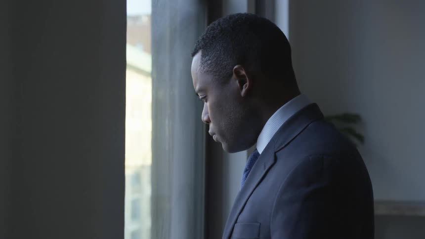 A businessman stands in front of a window