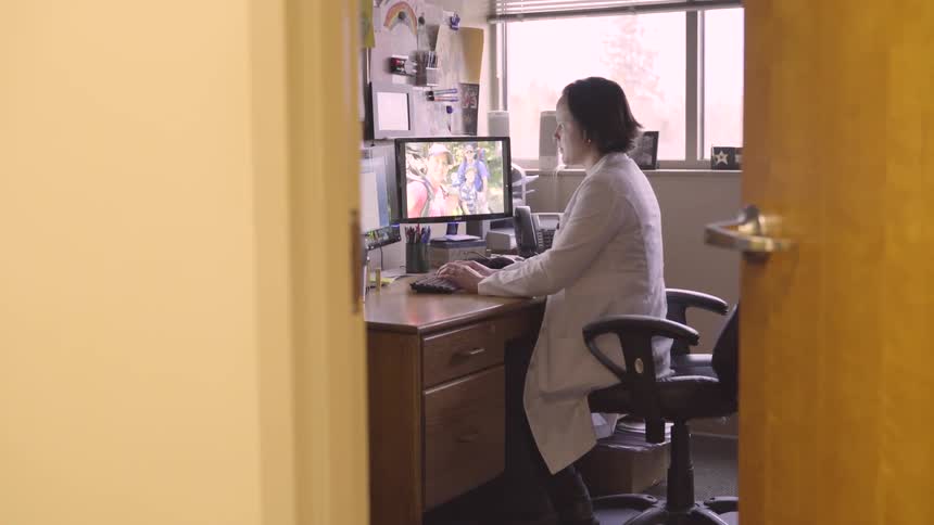 A woman sits at a desk in an office working at a computer during the day
