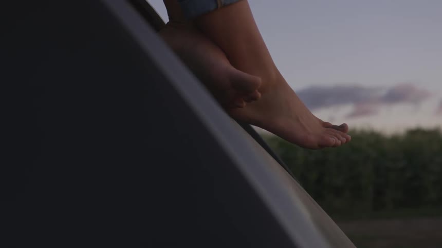 A person's feet are dangling from the car