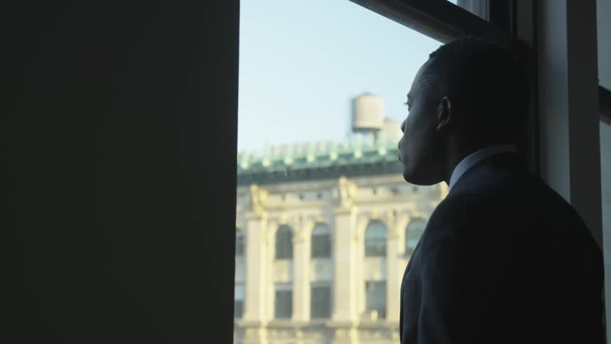 A man looks out the window of the city