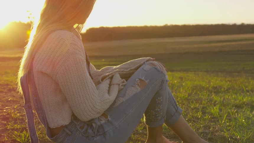 Woman sits outside in a grassy field