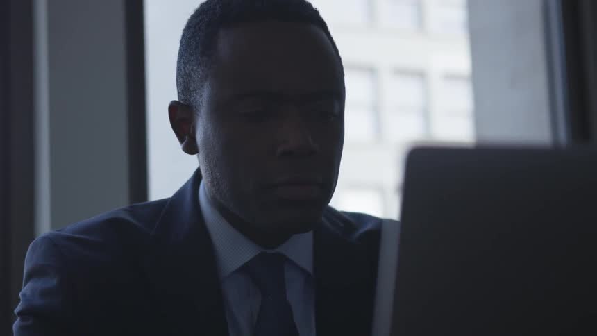 Man in suit is sitting in front of laptop in city building