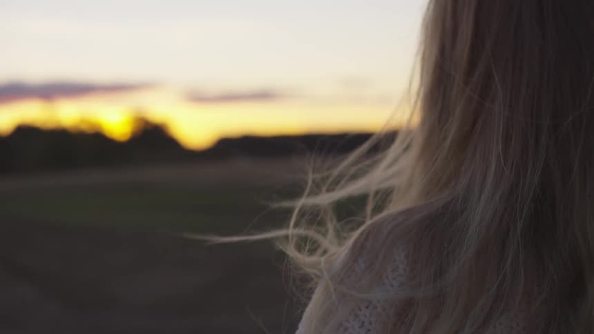 Woman stands outside on a windy evening