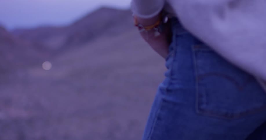 A person is standing in the desert watching a car drive up