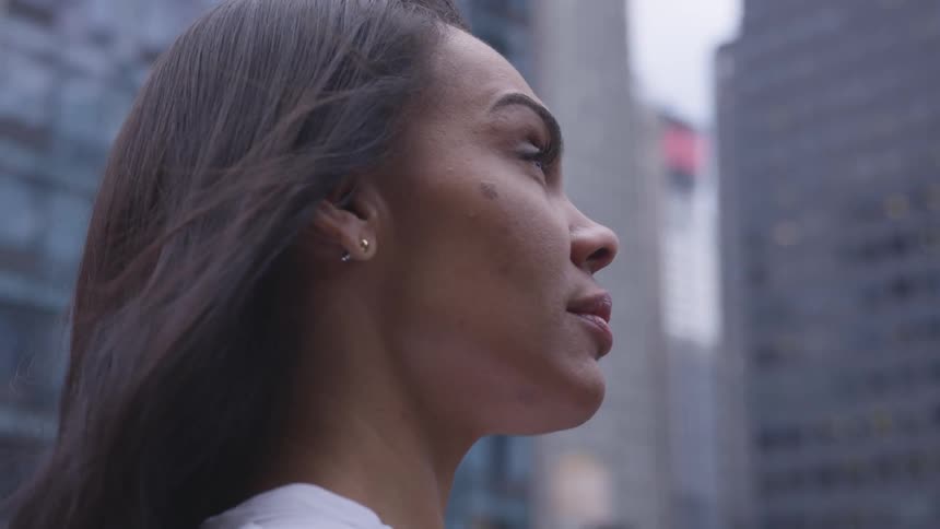 A woman stands in the city on a windy day