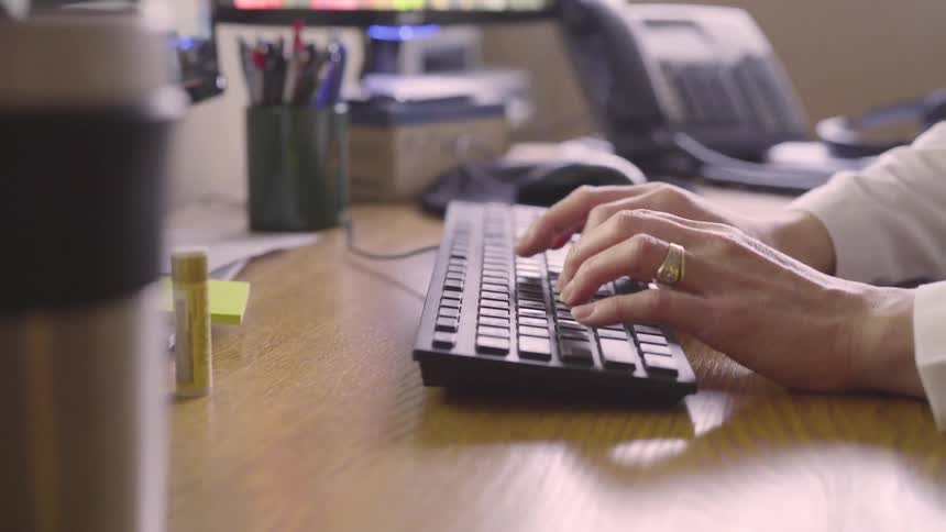 A woman types on a keyboard in an office