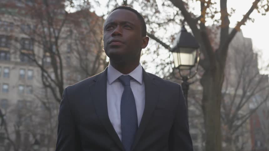 A businessman walks on a city sidewalk