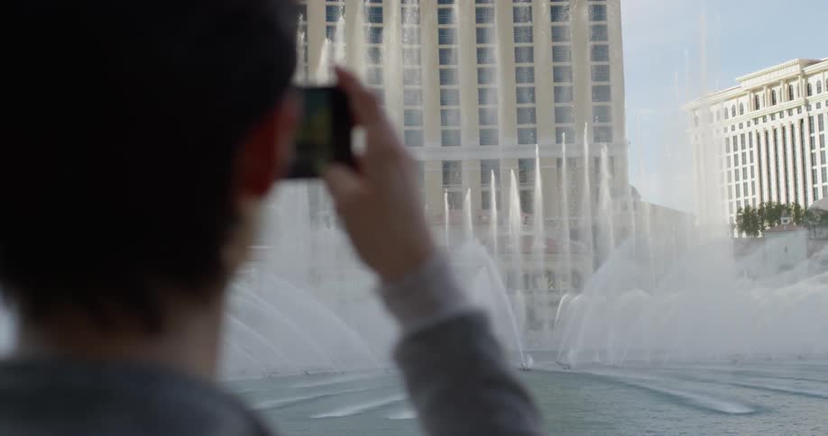 A woman takes a picture of fountains in las vegas