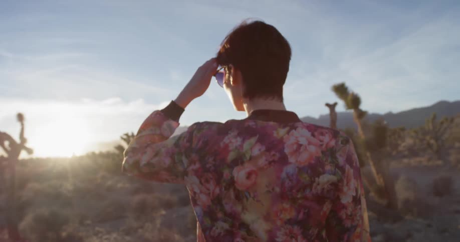Woman walks through the vegetation in the field on a sunny day