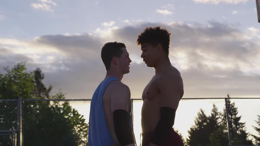 Two athletes get into an argument on an outdoor athletic field at sunset