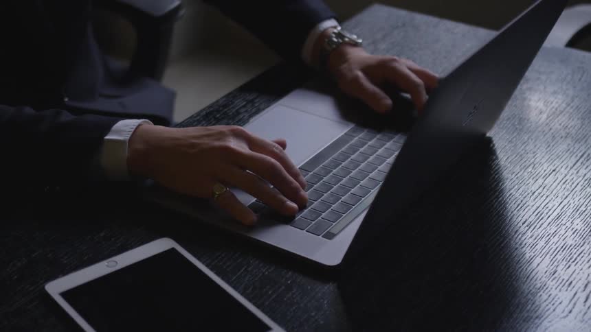A businessman types on a laptop
