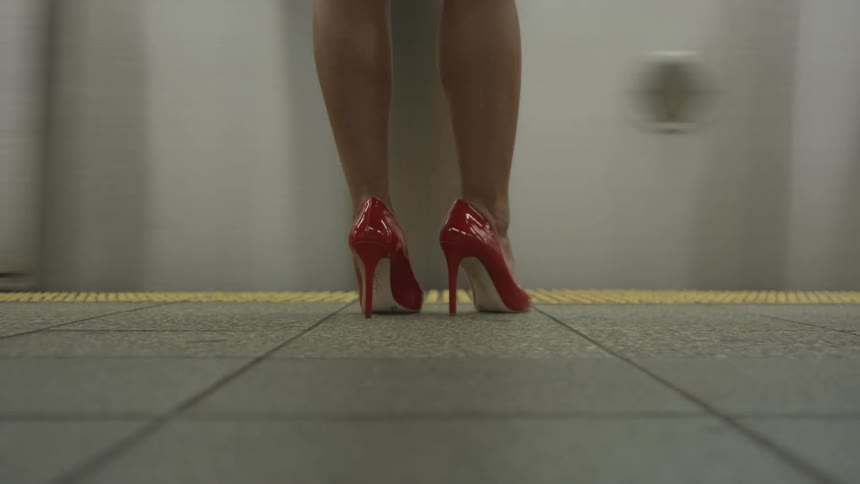 A woman in red heels waits for a subway train