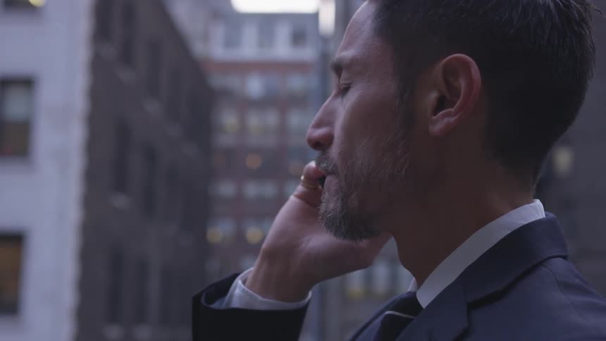 A man wearing a suit talks on his phone on a city street