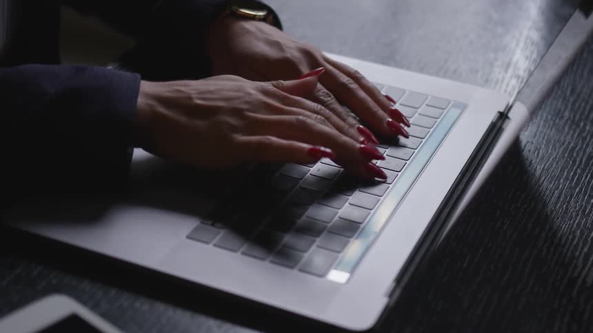 A woman types on a laptop keyboard