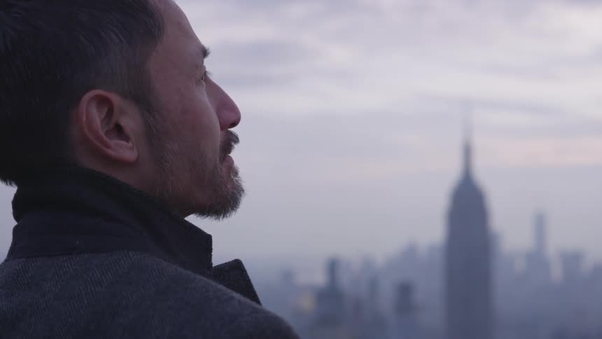 A man stands outside in a city at sunset