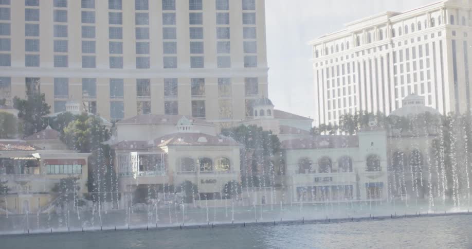 Woman looks at fountains spraying up in front of a hotel