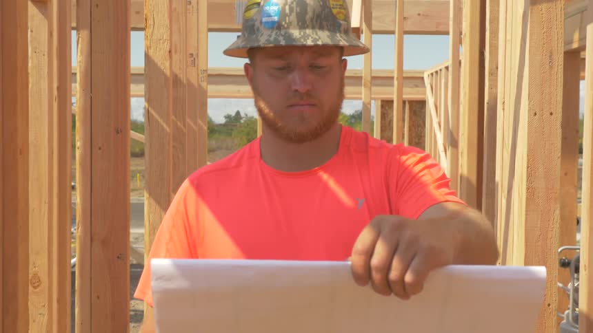 The man is looking at blueprints on a construction site