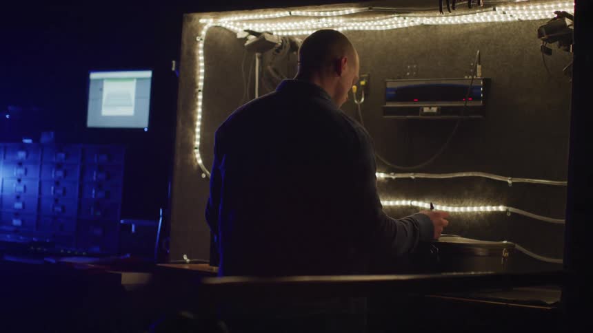 Man signs a piece of paper with a pen in a dimly lit room